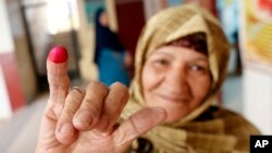 Una mujer muestra su dedo entintado después de emitir su voto en enmiendas constitucionales durante el segundo día de votación de tres días en una mesa electoral en El Cairo, Egipto, 21 de abril de 2019.