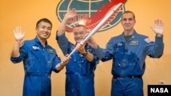 Los tripulantes de la expedición 38, el ingeniero de vuelo japonés Koichi Wakata, el comandante ruso del cohete Soyuz, Mikhail Tyurin y el ingeniero de vuelo estadounidense de la NASA Rick Mastracchio, posan con la antorcha Olímpica previo a su partida.