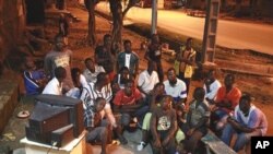 A group of young men watch the announcement of final provisional presidential election results shortly after midnight on the streets of a closed-up Bouake, in northern Ivory Coast, 04 Nov 2010