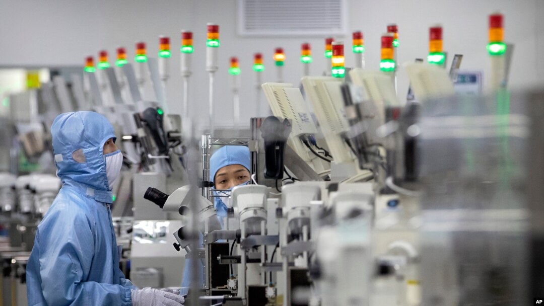 Employees wearing protective equipment work at a semiconductor production facility for Renesas Electronics during a government organized tour for journalists in Beijing, May 14, 2020. 