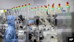 Employees wearing protective equipment work at a semiconductor production facility for Renesas Electronics during a government organized tour for journalists in Beijing, May 14, 2020. 