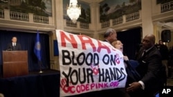 Activist Medea Benjamin, of Code Pink, is led away by security as she protests during a statement by National Rifle Association executive vice president Wayne LaPierre, left, during a news conference in Washington, December 21, 2012.
