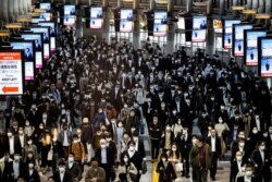 Para pengguna angkutan umum mengenakan masker saat berjalan di Stasiun Shinagawa, Tokyo, 19 November 2020.