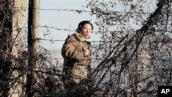 A North Korean female soldier stands watch along the bank of the Yalu River, the China-North Korea border river, near North Korea's town of Sinuiju, 25 Nov 2010
