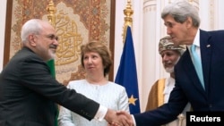 U.S. Secretary of State John Kerry (R) and Iranian Foreign Minister Javad Zarif (L) shake hands as Omani Foreign Minister Yussef bin Alawi (2nd R) and EU envoy Catherine Ashton watch in Muscat Nov. 9, 2014. 