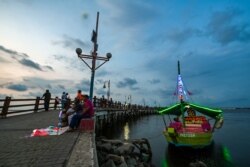 Warga menikmati suasana matahari tenggelam di Teluk Jakarta, 7 Juni 2019, sehari sebelum Hari Laut Sedunia. (AFP)