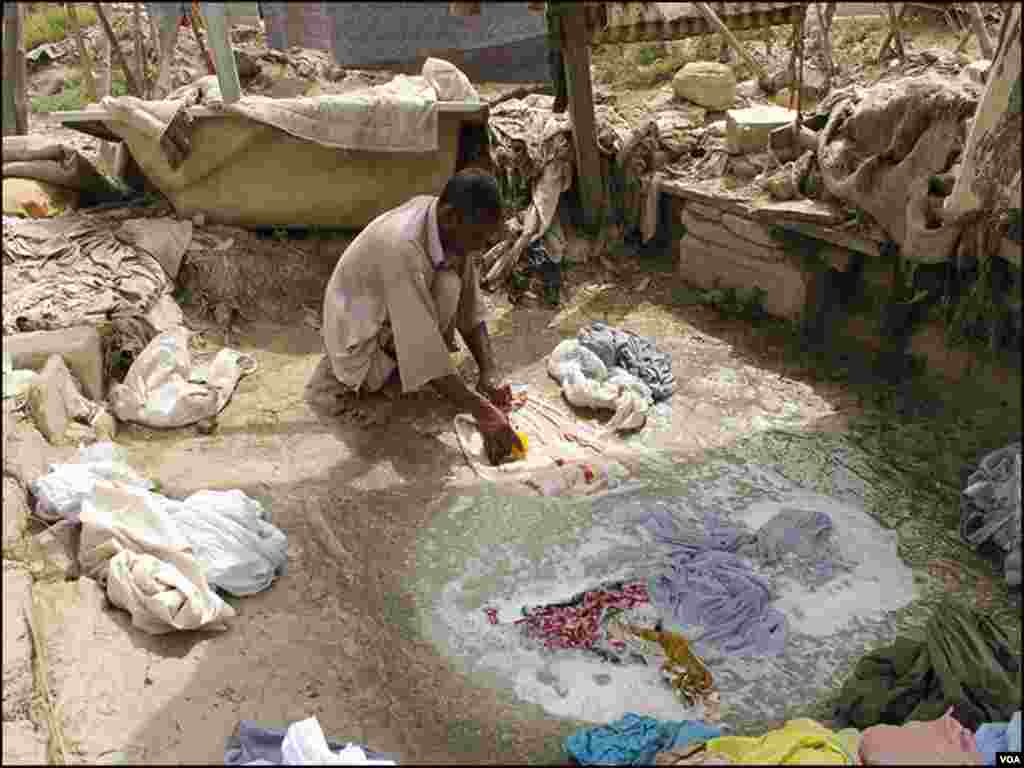 دھوبی گھاٹ میں ایک دھوبی کپڑوں پر صابن لگا رہا ہے۔