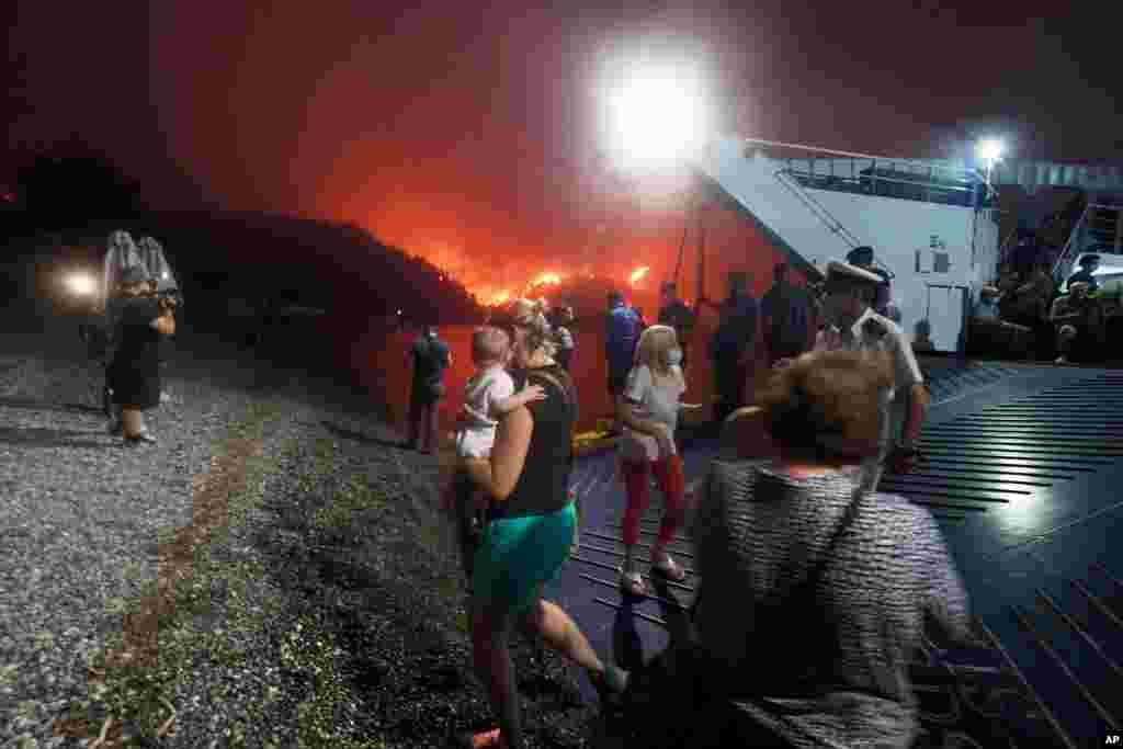 그리스 아테네에서 북쪽으로 160km 떨어진 에비아섬의 림니 마을에 산불이 퍼지자 사람들이 배로 대피하고 있다. 