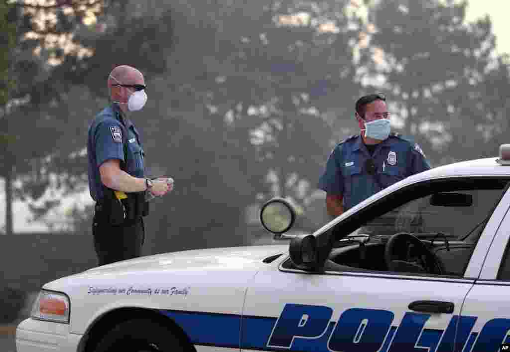 Colorado Springs police officers wear masks for smoke as they man a roadblock to an evacuated area of forest, ranches and residences, in the Black Forest wildfire area, Colorado, June 13, 2013.
