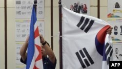 Dua petugas Komite Penyelenggara Asian Games Indonesia (INASGOC), memasang bendera Korea Utara di samping bendera Korea Selatan sebelum pertemuan Dewan Olimpiade Asia di Jakarta, 28 Juni 2018.