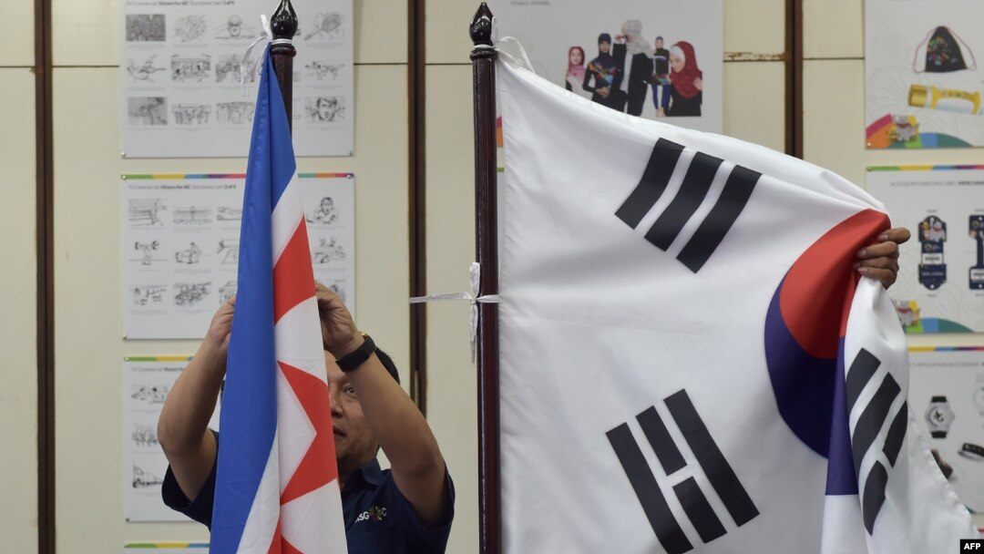 Petugas dari Indonesian Asian Games Organising Committee (INASGOC) memasang bendera Korea Utara di samping bendera Korea Selatan sebelum pertemuan Dewan Olimpiade Asia di Jakarta, 28 Juni 2018.