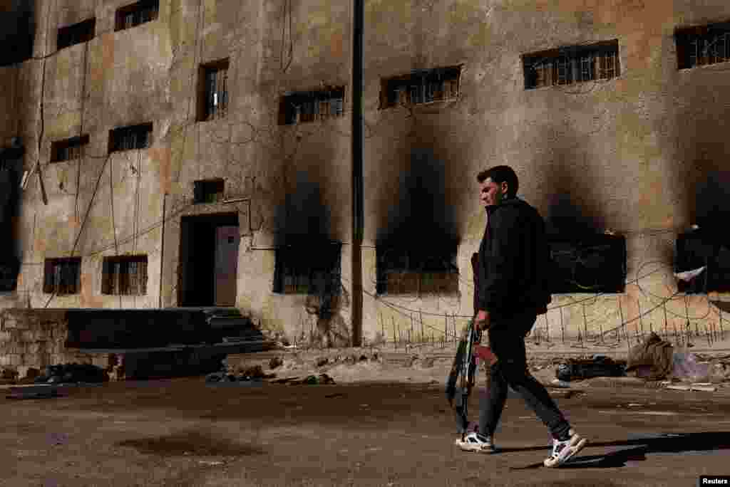 A man carrying a rifle searches for his cousin who was detained in Sednaya prison, which was known as a slaughterhouse under Syria&#39;s Bashar al-Assad rule, in Sednaya.