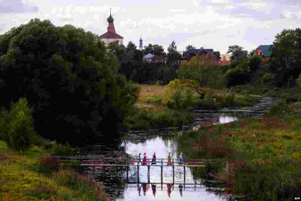 People cross the river on a wooden bridge in Suzdal, a tourist spot, a part of ancient Russian cities, known as the "Golden Ring".