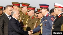 Iraqi Prime Minister Haider al-Abadi, second from left, shakes hands with military officials with Iraq Defense Minister Khaled al-Obeidi, left, during the Iraqi Army Day anniversary celebration, in Baghdad, Jan. 6, 2015. 