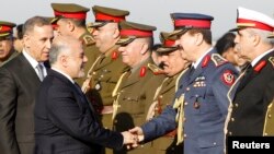 FILE - Iraqi Prime Minister Haider al-Abadi, second from left, shakes hands with military officials with Iraq Defense Minister Khaled al-Obeidi, left, during the Iraqi Army Day anniversary celebration, in Baghdad, Jan. 6, 2015. 