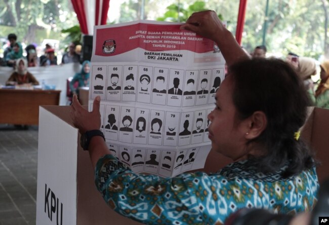 Seorang perempuan memperlihatkan contoh surat suara pemilu legislatif dalam simulasi yang digelar Komisi Pemilihan Umum di Jakarta, 10 April 2019.