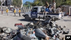 A police vehicle drives past wreckage after a suicide car bomb attack on a government building in Mogadishu, Somalia, March 23, 2019. Al-Shabab gunmen stormed the government building after a suicide car bombing.