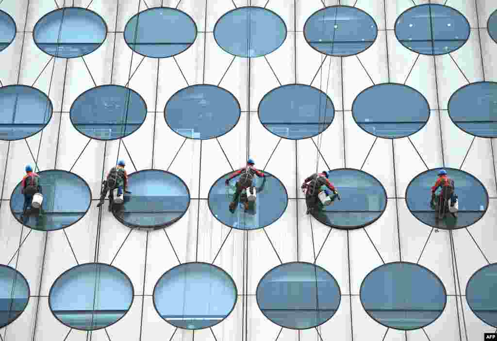 Workers clean the windows of a building in Beijing, China.