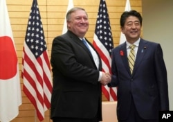 U.S. Secretary of State Mike Pompeo, left, shakes hands with Japanese Prime Minister Shinzo Abe at Abe's office in Tokyo, Oct. 6, 2018.