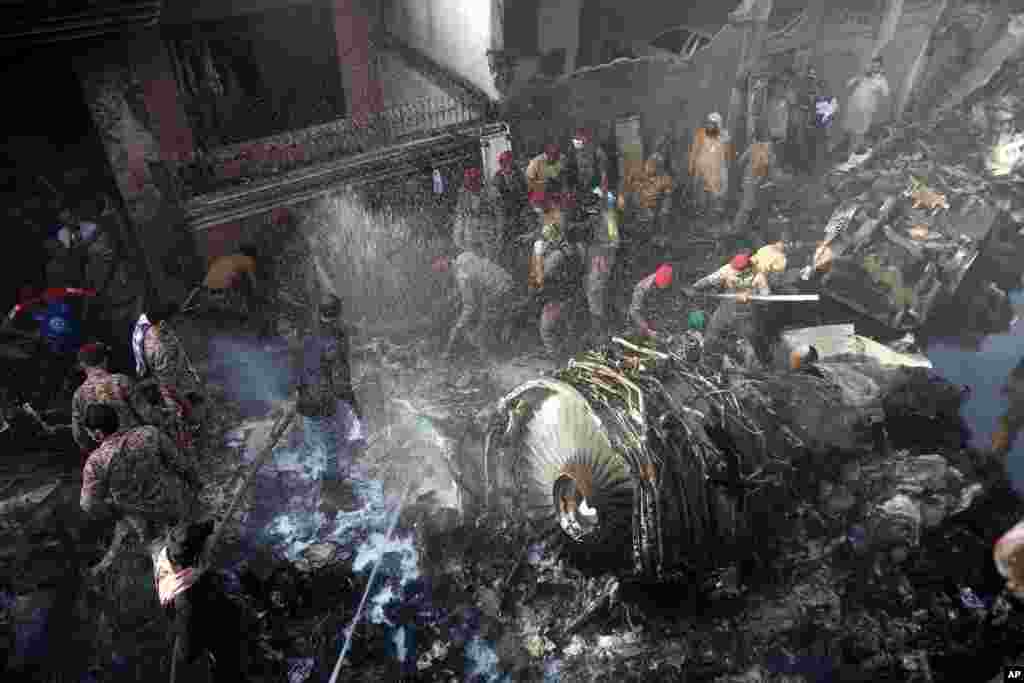 Rescue workers and local residents search for survivors in the wreckage of a plane that crashed with nearly 100 people onboard in a residential area of Karachi, Pakistan, May 22, 2020.
