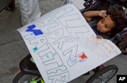 Owen Munoz, 2, holds a sign as his mother, Mia, joins a group protesting the separated of immigrant families caught on the southwest border near San Diego, Calif., as the group rallies at the federal building in Los Angeles, June 23, 2018.