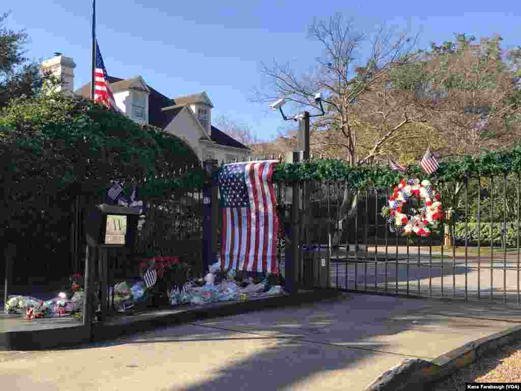 Flores y banderas dejadas por dolientes crean un memorial improvisado afuera de la casa del expresidente George H.W. en Houston, Texas, el 5 de diciembre de 2018.