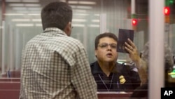 FILE - A Customs and Border Protection officer checks the passport of a nonresident visitor to the United States inside immigration control at McCarran International Airport, in Las Vegas, Dec. 13, 2011. 