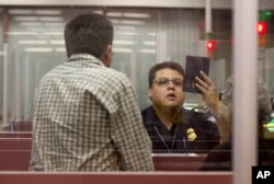 FILE - A Customs and Border Protection officer checks the passport of a nonresident visitor to the United States inside immigration control at McCarran International Airport, in Las Vegas, Dec. 13, 2011.