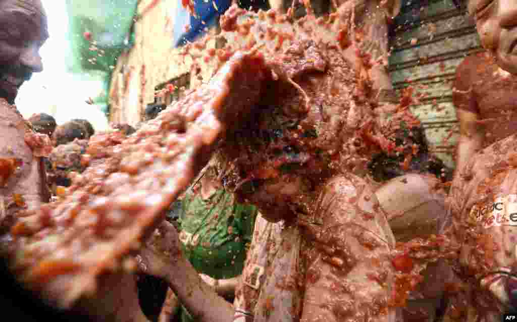 A reveler is pelted with puree of smashed tomatoes during the 'Tomatina' festival in Bunol, Spain.