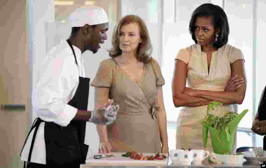 Valerie Trierweiler, partner of Francois Hollande, and first lady Michelle Obama watch a student explain the making of a meal during a tour of the Gary Corner Youth Center in Chicago.