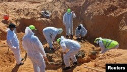 FILE - Members of the Government of National Accord's missing persons bureau exhume bodies in what Libya's internationally recognized government officials say is a mass grave, in Tarhouna city, Libya, October 27, 2020.