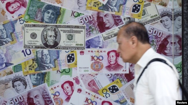 中国香港，一名男子经过一家外汇商店的广告，该广告宣传人民币、美元和欧元兑换服务。