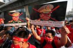 Warga Myanmar yang tinggal di Thailand, memegang foto Panglima Tertinggi militer Myanmar Jenderal Min Aung Hlaing saat melakukan aksi protes di depan Kedutaan Besar Myanmar, di Bangkok, Thailand, Senin, 1 Februari 2021.