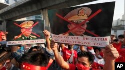 Des Birmans vivant en Thaïlande tiennent des photos du commandant en chef militaire du Myanmar, le général Min Aung Hlaing, lors d'une manifestation devant l'ambassade du Myanmar à Bangkok, en Thaïlande, le lundi 1er février 2021.