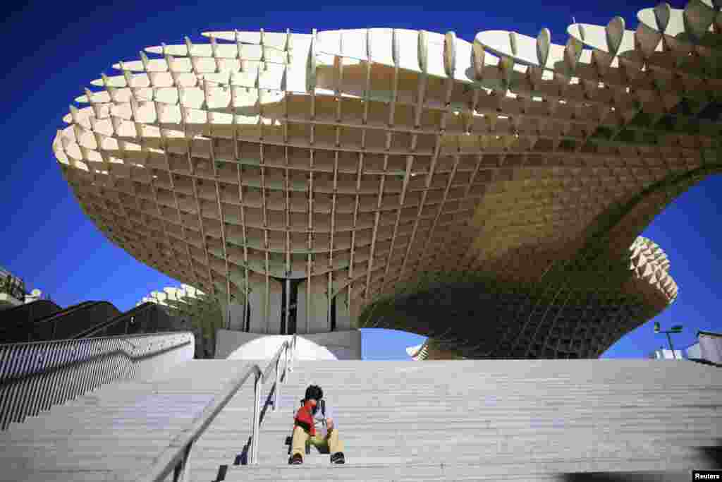 A man reads on the stairs in front of the world's largest wooden structure "Metropol Parasol" in the Andalusian capital of Seville, southern Spain. 