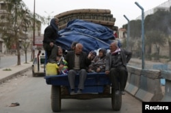 FILE - People ride in a truck with their belongings in the center of Afrin, Syria, March 24, 2018.