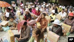 People sit as they receive flood donations at downtown Phnom Penh, Thursday, Oct. 13, 2011. 