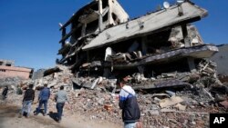 People walk past ruined buildings in Cizre, Turkey, early Wednesday, March 2, 2016.