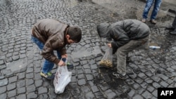Children collect bullet shells off the streets of Sur district, on December 30, 2015 in the mainly Kurdish city of Diyarbakir, after a curfew was partially lifted.