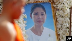 A Buddhist monk leads a funeral procession past a portrait photo of Ouk Phalla, Prince Norodom Ranariddh wife, during her cremation ceremony, in Phnom Penh, Cambodia, Wednesday, June 20, 2018. Ouk Palla was killed in a car driven by Ranariddh who himself was seriously injured early June 17. (AP Photo/Heng Sinith)