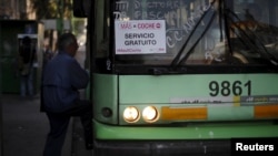 A passenger boards an electric bus displaying a sign that reads "MasXCoche. Free Service" in Mexico City, Mexico, April 5, 2016. 