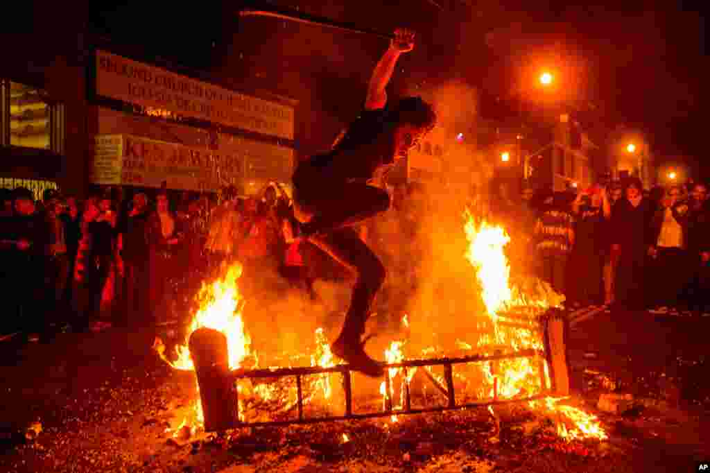 A man jumps over a burning couch in the Mission District after the San Francisco Giants beat the Kansas City Royals to win the World Series, San Francisco, Oct. 29, 2014. 