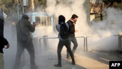 FILE - Iranian students run for cover from tear gas at the University of Tehran during a demonstration, in the capital Tehran, Iran, Dec. 30, 2017. 