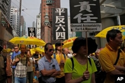 FILE - Pro-democracy protesters carry placards that read "Vindicate June 4th" during a demonstration in Hong Kong, May 26, 2019.