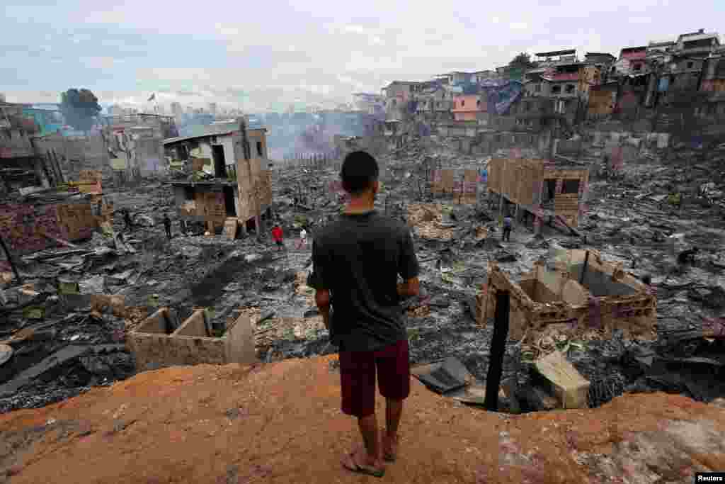 A resident is seen after a fire at Educandos neighborhood, on a branch of the Rio Negro, a tributary to the Amazon river, in the city of Manaus, Brazil.