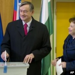 Slovenia's president Danilo Turk, left, casts his ballot as his wife Barbara Miklic, right, looks on at a polling station in Ljubljana, December 4, 2011.