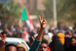 Pro-democracy protesters flash the victory sign as they take to the streets to condemn a takeover by military officials, in Khartoum, Sudan, Oct. 25, 2021.