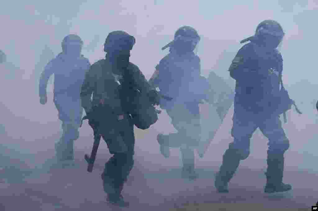 Riot police run in a cloud of teargas during clashes with anti-government coca farmers near the coca market in La Paz, Bolivia, Oct. 4, 2021.