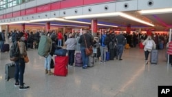 Passengers queue at London Heathrow Airport's T3 as the US reopens its borders to UK visitors in a significant boost to the travel sector, in London, Monday, Nov. 8, 2021. (Steve Parsons/PA via AP)