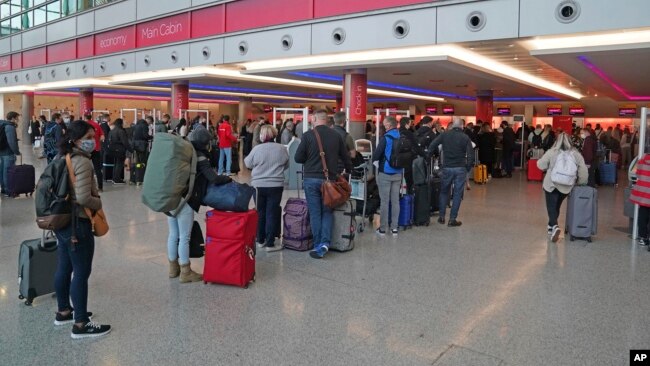 Passengers queue at London Heathrow Airport's T3 as the US reopens its borders to UK visitors in a significant boost to the travel sector, in London, Monday, Nov. 8, 2021. (Steve Parsons/PA via AP)